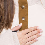 The 686 Ladies Hemlock Fleece Hoodie 2023 has an ivory-colored background with a brown stripe running down the center and three large bronze buttons.