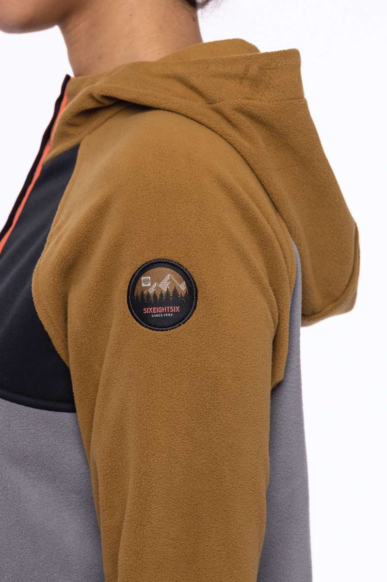 The 686 Ladies Hemlock Fleece Hoodie 2023 in tan features an insulated hood and a zippered chest pocket.