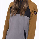 A woman wearing a brown and gray 686 Ladies Hemlock Fleece Hoodie with an insulated hood and front snap buttons.