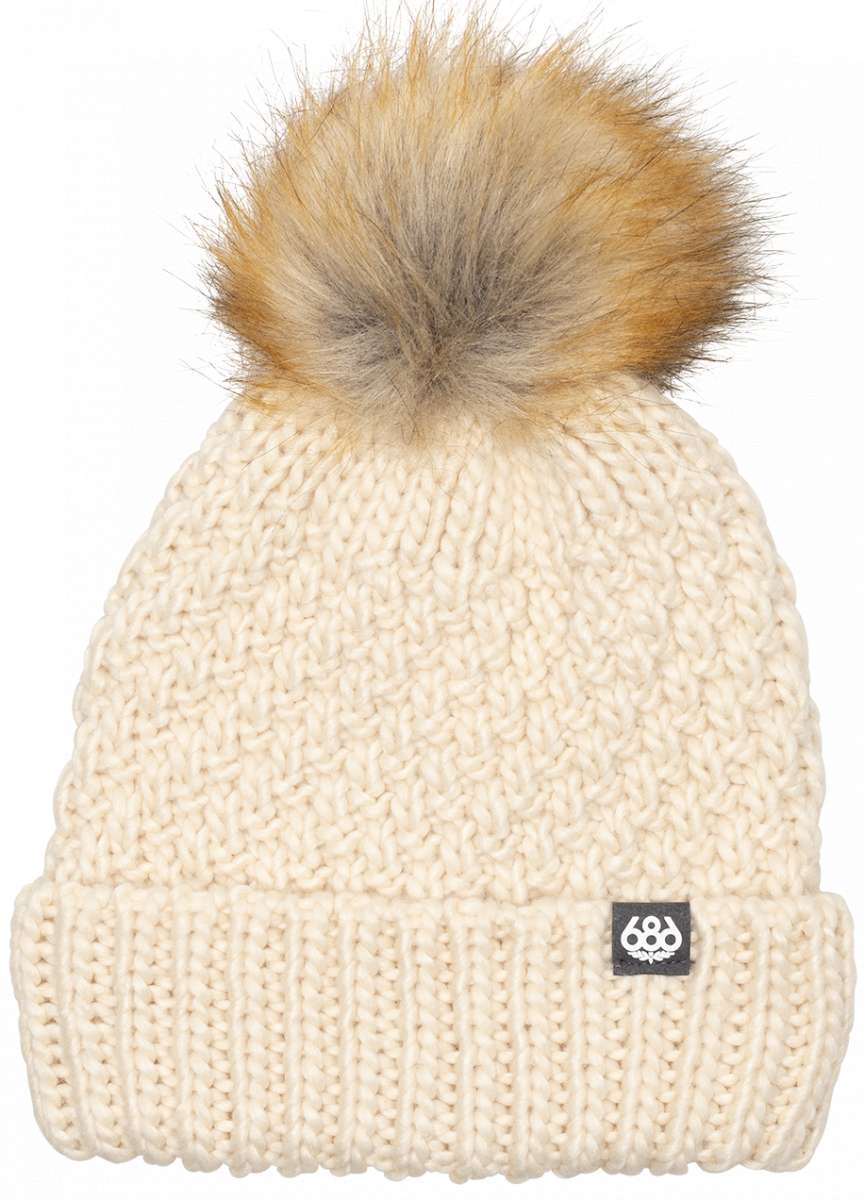 The 686 Majesty Beanie is crafted from cream-colored cable knit fabric and features a fluffy brown faux fur pom-pom on top.