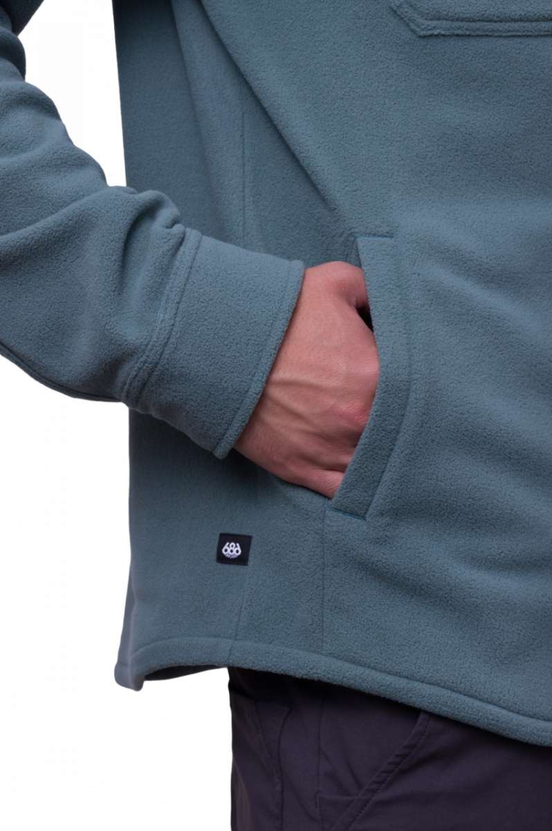 The 686 Sierra Fleece Flannel 2024 is depicted in teal with two front pockets and an adjustable drawstring at the waist.