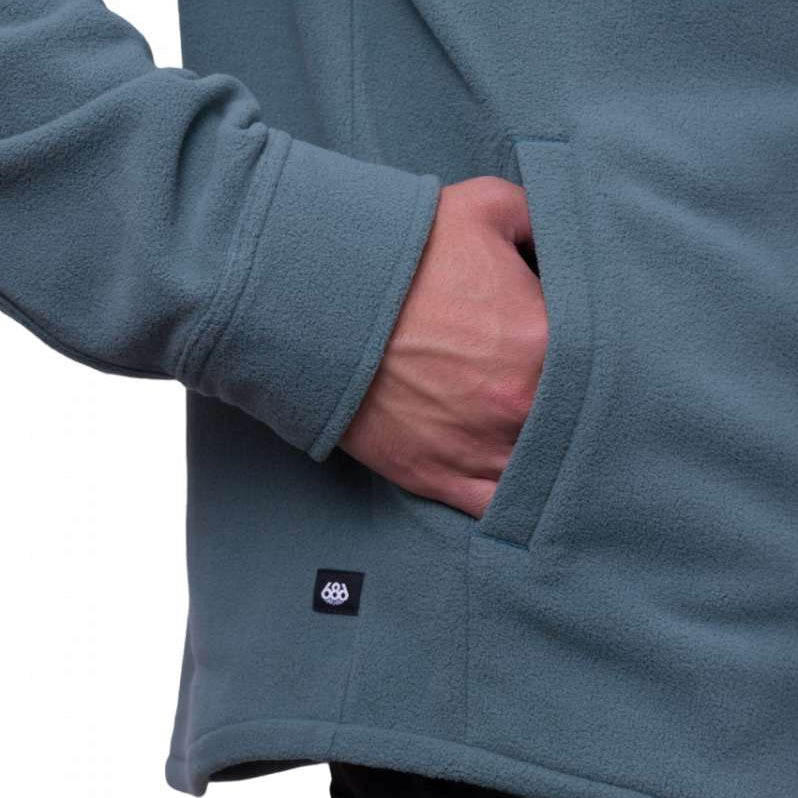 The 686 Sierra Fleece Flannel 2024 is depicted in teal with two front pockets and an adjustable drawstring at the waist.