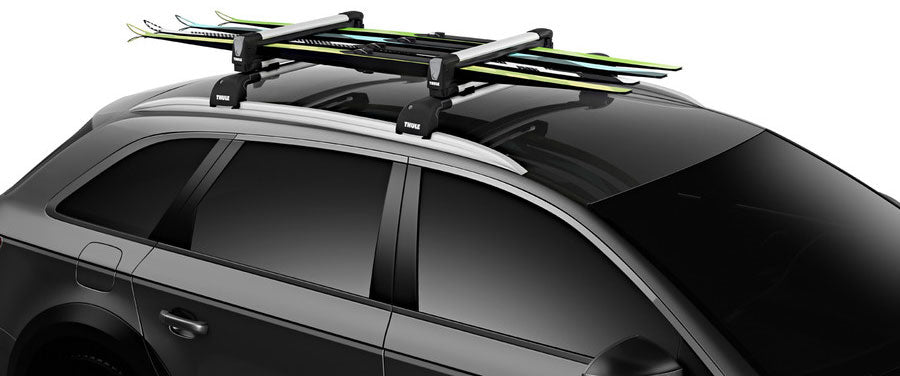Thule Snowpack M 4 Pairs - This image shows a black plastic roof rack with four pairs of skis mounted on top, each pair secured by two black straps and one yellow strap.