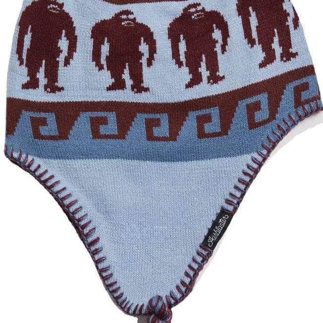 Airblaster Squatchamama Beanie 2023 - A light blue beanie with a brown pattern of Bigfoot-like creatures and geometric shapes.