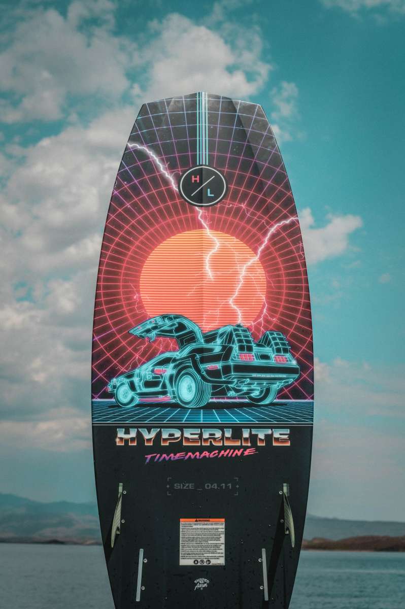 Hyperlite Time Machine Limited Edition Wakesurf Board 2022 - A black wakesurf board with a neon blue and pink design featuring a DeLorean car, set against a red circle background.