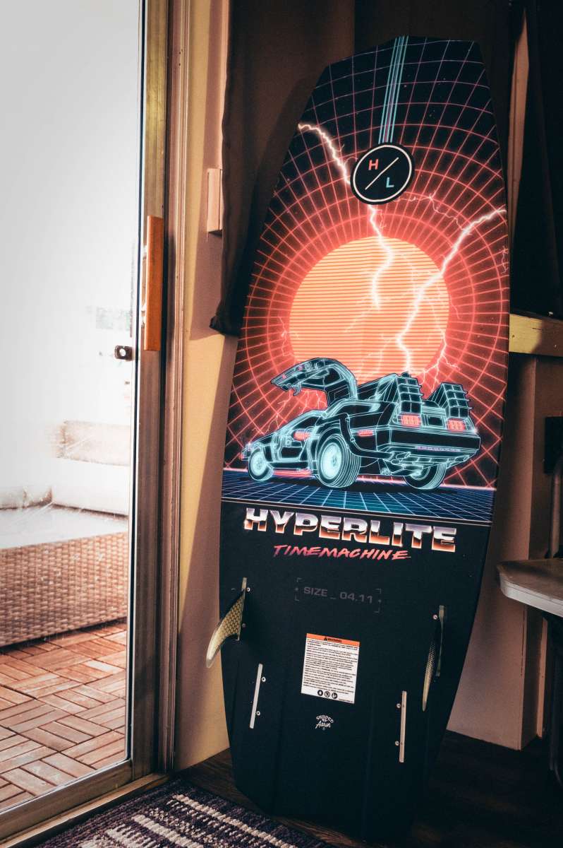 Hyperlite Time Machine Limited Edition Wakesurf Board 2022 - A black board with a red and white graphic of a DeLorean car, featuring a grid pattern background.