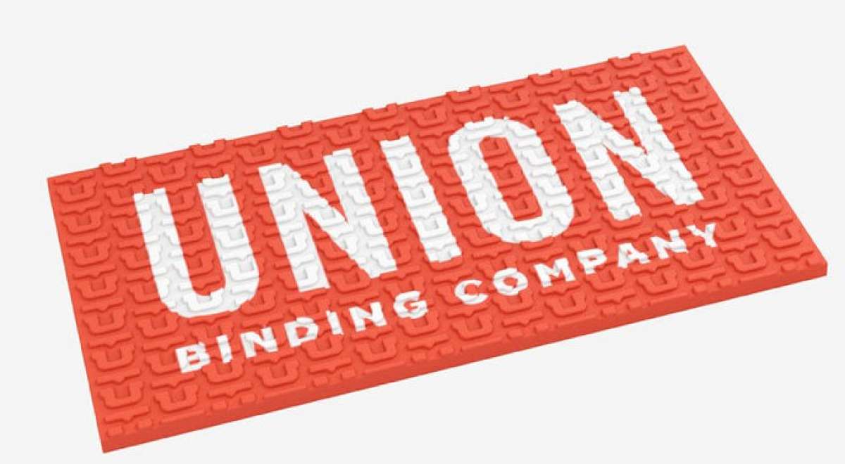 Union Surf Stomp Pad - A coral-colored pad with a textured surface, featuring a repeating pattern of stylized "U" letters in white.