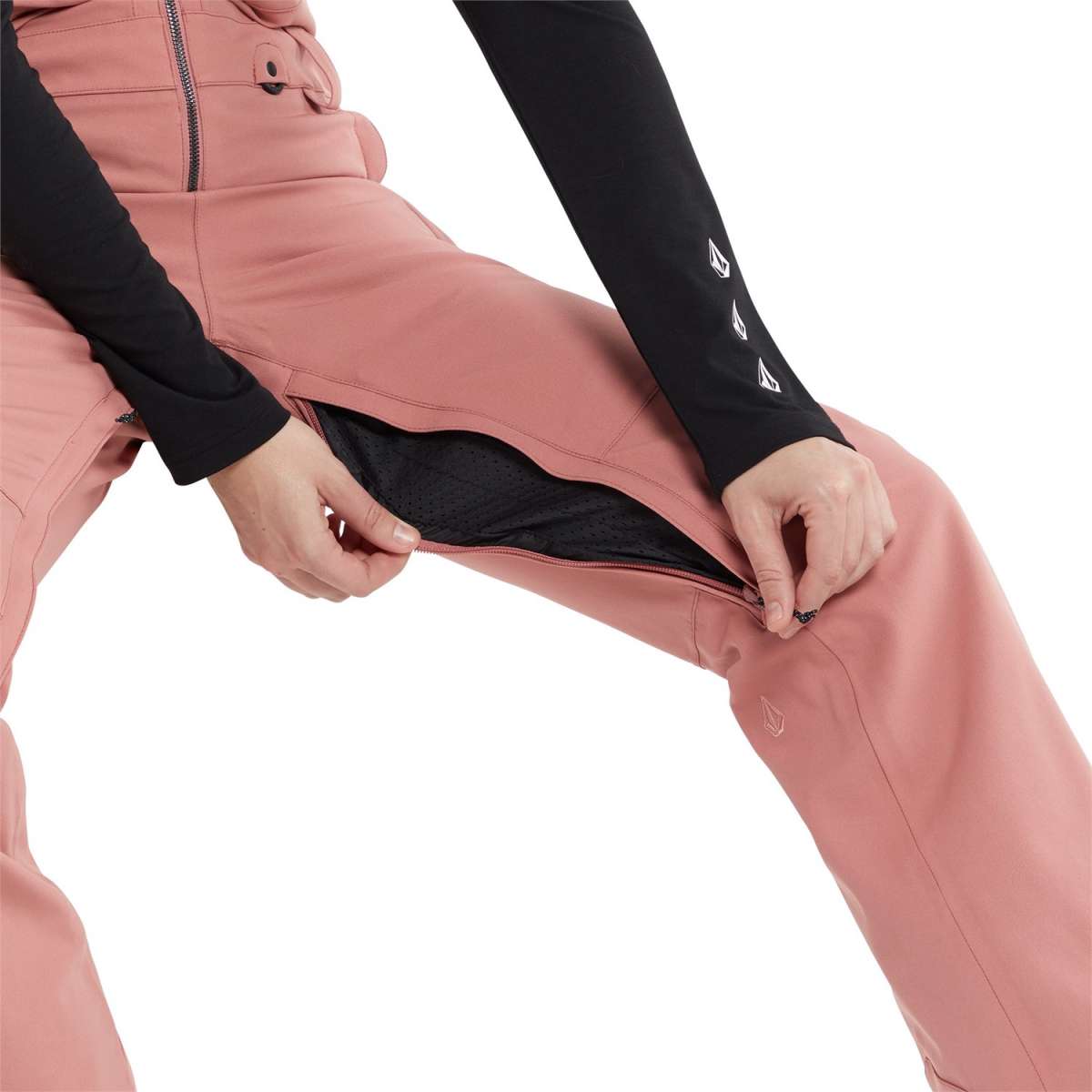 Volcom Women's Swift Bib Overall Pant 2024 - A dusty rose-colored overall with a black zipper and two front pockets, worn by a model against a white background.