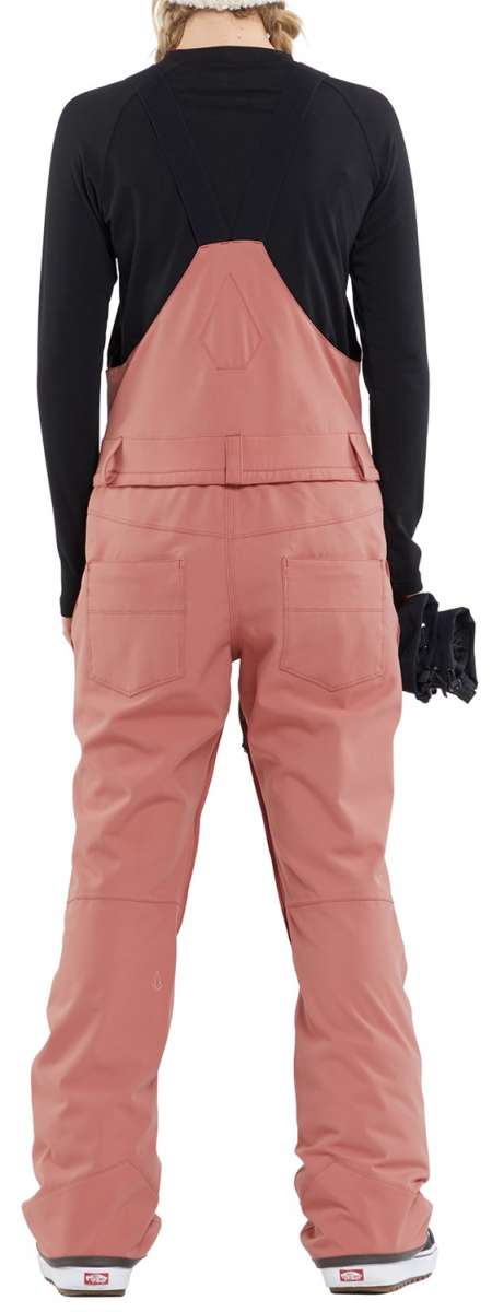 Volcom Women's Swift Bib Overall Pant 2024 - A dusty rose bib overall pant with a geometric pattern on the back, featuring two front pockets and a zippered fly.