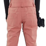 Volcom Women's Swift Bib Overall Pant 2024 - A dusty rose bib overall pant with a geometric pattern on the back, featuring two front pockets and a zippered fly.