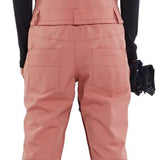 Volcom Women's Swift Bib Overall Pant 2024 - A dusty rose bib overall pant with a geometric pattern on the back, featuring two front pockets and a zippered fly.