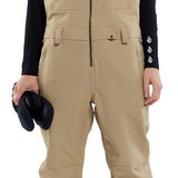 Volcom Women's Swift Bib Overall Pant - Tan bib overalls with zippered front and adjustable straps.