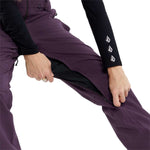 Volcom Women's Swift Bib Overall Pant - A pair of purple snowboard pants with a black zipper and white logo on the left leg.