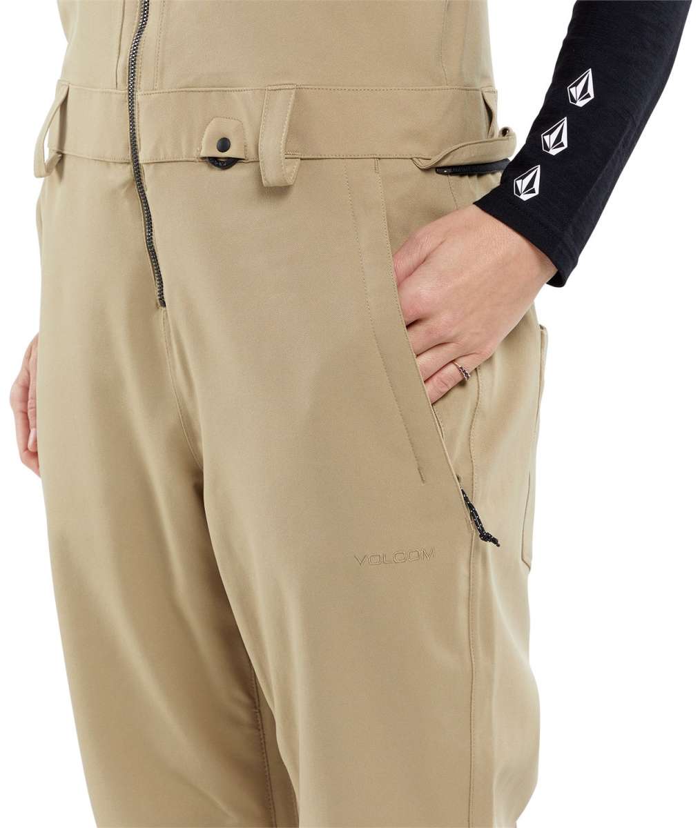 Volcom Women's Swift Bib Overall Pant 2024 - A pair of khaki-colored bib overalls with a zippered fly and adjustable straps.