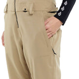 Volcom Women's Swift Bib Overall Pant 2024 - A pair of khaki-colored bib overalls with a zippered fly and adjustable straps.