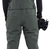 Volcom Women's Swift Bib Overall Pant 2024 - Dark green bib overalls with a black top and white soles on the feet in the image.