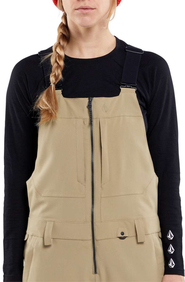 Volcom Women's Swift Bib Overall Pant 2024 - A pair of khaki-colored bib overalls with a zippered front and adjustable straps.