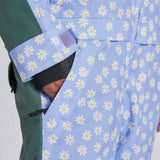 Airblaster Women's Freedom Insulated Suit 2024 - A light blue snowsuit with a repeating pattern of white flowers and yellow centers, featuring a green sleeve on the left side.