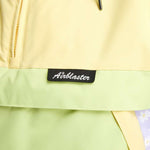 Airblaster Women's Trenchover Insulated Jacket 2022 - A pastel yellow jacket with a black zipper and drawstring at the waist.