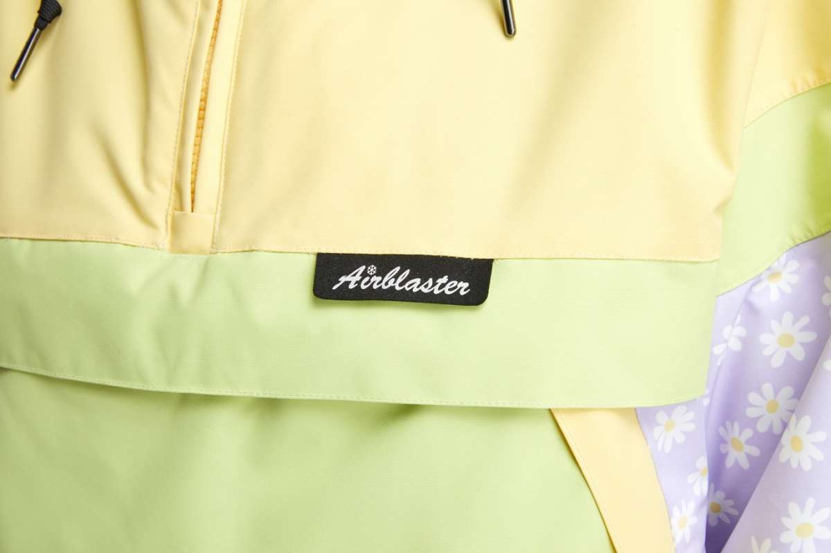 Airblaster Women's Trenchover Insulated Jacket 2022 - A pastel yellow jacket with a black zipper and drawstring at the waist.