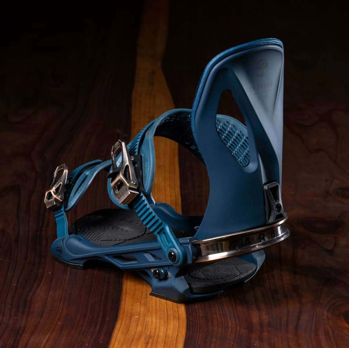 Arbor Cypress Snowboard Binding 2023 - A blue snowboard binding with a black strap and silver buckles, featuring a textured pattern on the baseplate.
