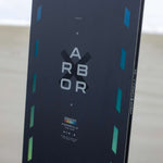 Arbor Formula Rocker Snowboard 2024 - A black snowboard with a geometric pattern of white lines and shapes on top of a snowy background.