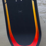 Arbor Formula Rocker Snowboard 2024 - A black snowboard with a yellow and red gradient stripe along its bottom edge.
