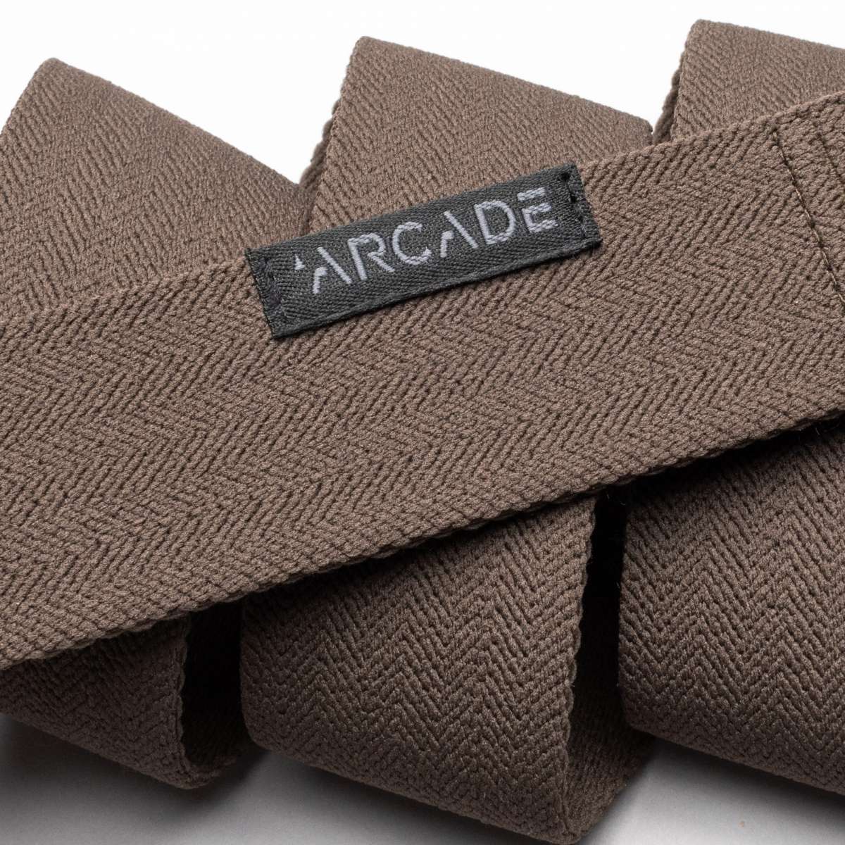 Arcade Ranger Belt 2023 - Brown belt with a repeating geometric pattern of small triangles in lighter brown, on a textured woven fabric.