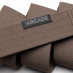 Arcade Ranger Belt 2023 - Brown belt with a repeating geometric pattern of small triangles in lighter brown, on a textured woven fabric.