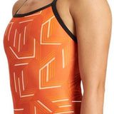 Arena Women's Puzzled Light Drop Back One Piece Swimsuit - A one-piece swimsuit with a light orange background and white geometric shapes, featuring thin straps and a high-cut leg.