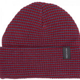 Autumn Stripe Beanie 2023 - A red beanie with blue stripes and a black label that says "AUTUMN" in white letters.
