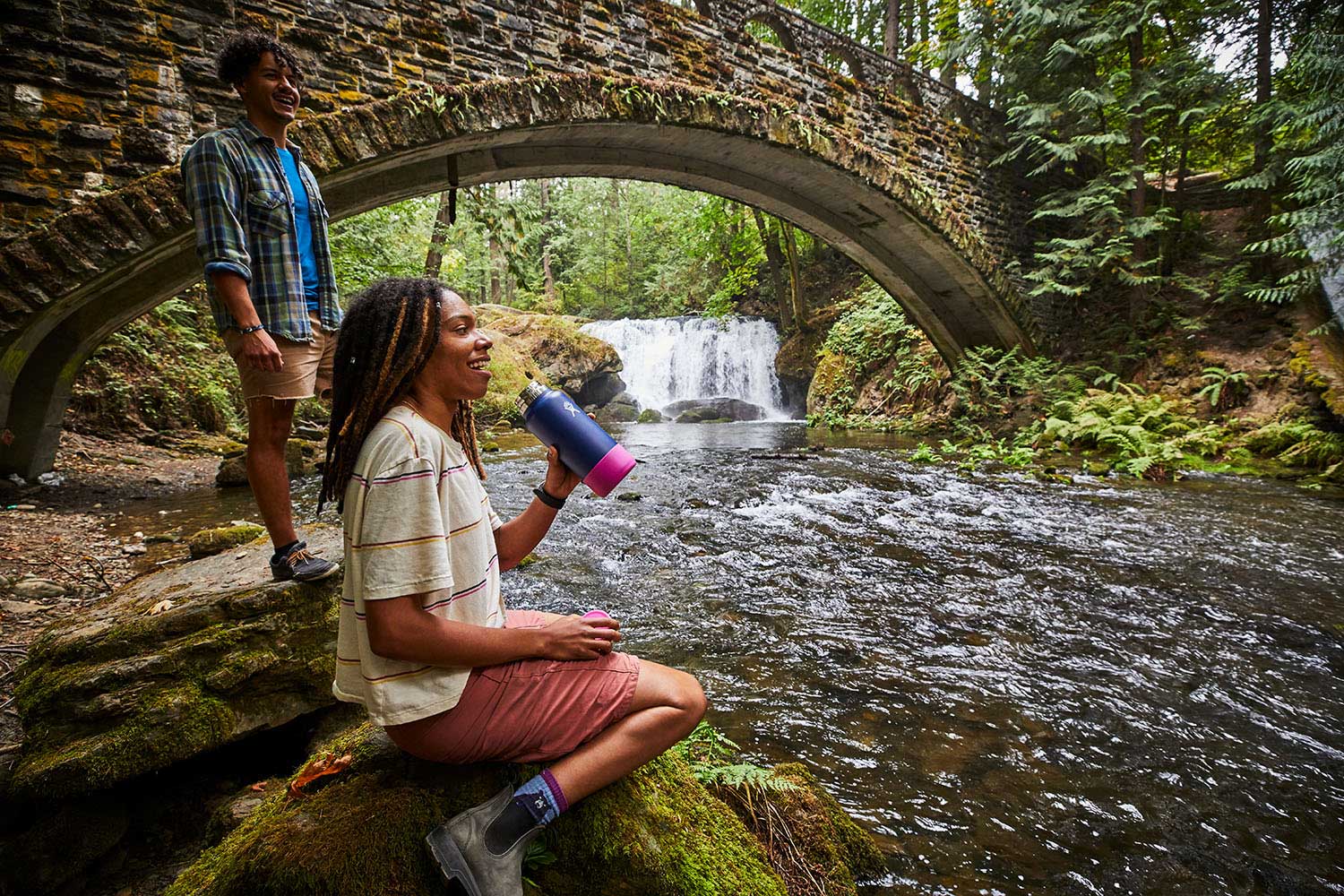 Hydro Flask Small Flex Bottle - Blue water bottle with a pink lid, held by a person wearing a white shirt and khaki shorts.