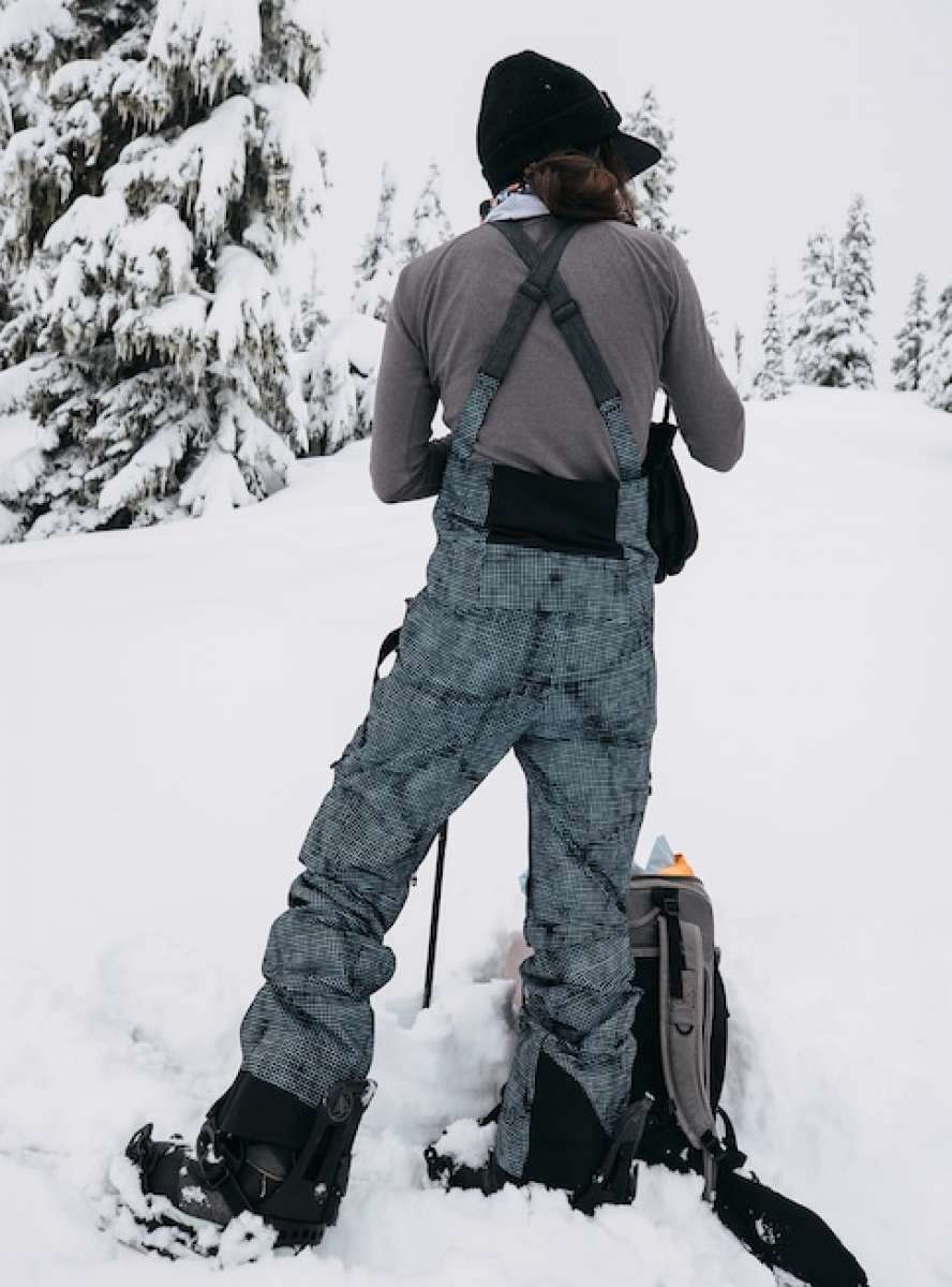 Burton Women's AK Gore-Tex Kimmy Bib Pant 2023 - A pair of black and white snow pants with a subtle grid pattern, featuring adjustable straps and buckles on the back.