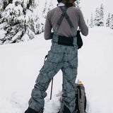 Burton Women's AK Gore-Tex Kimmy Bib Pant 2023 - A pair of black and white snow pants with a subtle grid pattern, featuring adjustable straps and buckles on the back.