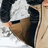 Burton Women's AK Gore-Tex Kimmy Bib Pant 2023 - A black bib pant with a zippered fly and adjustable waistband, featuring a snow-covered pine tree in the background.