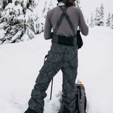 Burton Women's AK Gore-Tex Kimmy Bib Pant 2023 - Black bib pants with white stitching and a zippered pocket on the right thigh.