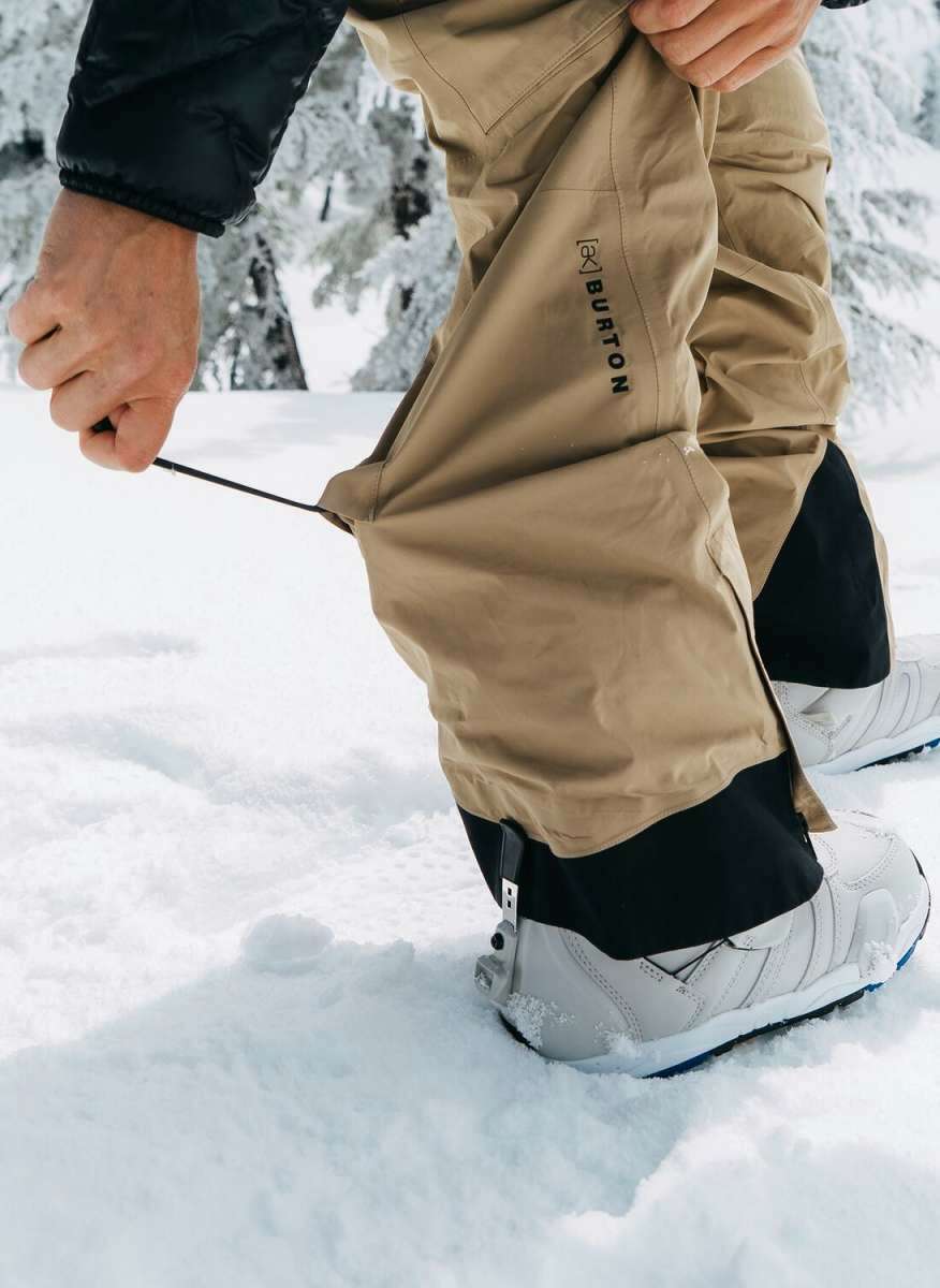 Burton Women's AK Gore-Tex Kimmy Bib Pant 2023 - A pair of khaki-colored snow pants with black accents and a zippered pocket on the thigh.