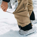 Burton Women's AK Gore-Tex Kimmy Bib Pant 2023 - A pair of khaki-colored snow pants with black accents and a zippered pocket on the thigh.