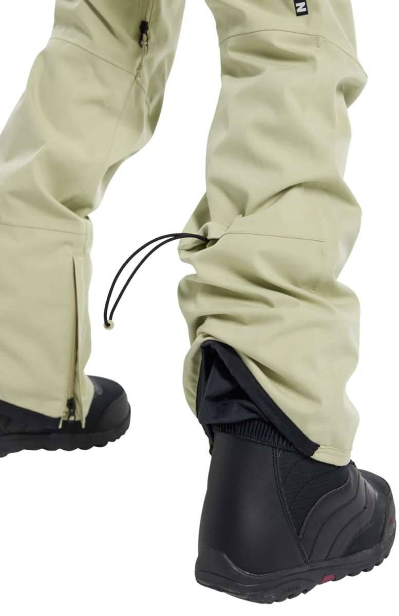 Burton Women's Gloria 2 Layer Stretch Pant 2024 - A pair of khaki-colored snow pants with a zippered pocket on the left thigh and a black drawstring at the waist.