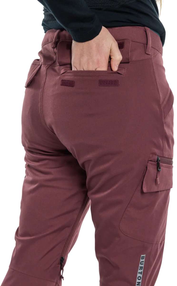 Burton Women's Gloria 2 Layer Stretch Pant 2024 - A pair of burgundy snow pants with a zippered pocket on the side and a small black zipper pull.