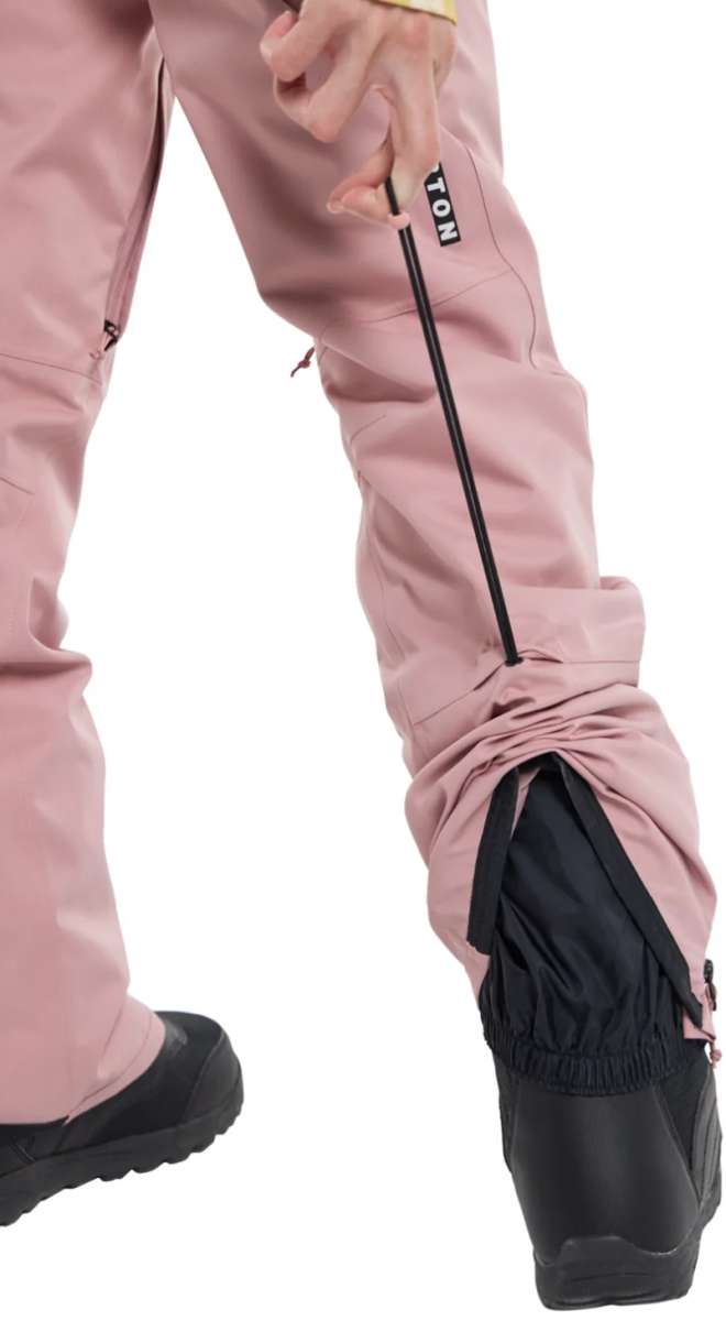 Burton Women's Marcy High Rise Stretch Pants 2024 - A pair of dusty rose-colored snow pants with a black zipper on the left leg and a white "BURTON" logo on the right thigh.