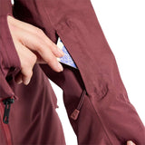 Burton Women's Pillowline GORE-TEX Insulated Jacket 2024 - A woman wearing a maroon jacket with a white logo on the left chest and a zipper pocket on the right side.