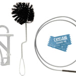 Camelbak Crux Cleaning Kit - A black, bristled brush with a long handle and looped end is shown next to a small, round bottle of cleaning solution.