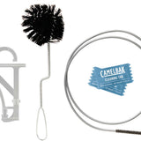 Camelbak Crux Cleaning Kit - A black, bristled brush with a long handle and looped end is shown next to a small, round bottle of cleaning solution.