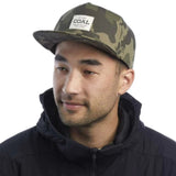 Coal Uniform Cap 2023 - A camouflage cap with a white rectangular patch on the front featuring the word "COAL" in black letters.