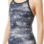 TYR Ladies' American Dream Diamondfit Swimsuit - A navy blue swimsuit with a pattern of faded white stars and stripes, featuring thin straps and a TYR logo on the upper left side.