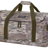Dakine EQ Duffle 50L 2022-2023 - A large, rectangular duffel bag with a zippered top and two dark green shoulder straps. It has a small black label on the front that reads "DAKINE" in white letters. The bag is made of a camouflage material featuring shades of brown, tan, and gray.