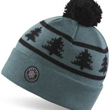 Dakine Jack Pine Merino Beanie 2024 - A light blue beanie with a black pine tree pattern and a black pom-pom on top.