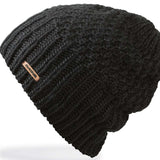 Dakine Ladies Zoe Beanie 2024 - A black beanie with a small, rectangular brown leather tag on the front.
