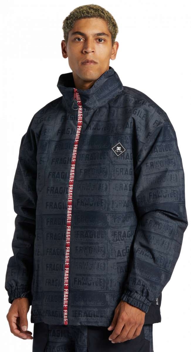 DC AW Vista Shell Jacket 2024 - A black jacket with a repeating pattern of "FRAGILE" labels in gray, featuring a red zipper and a small white logo on the left chest.